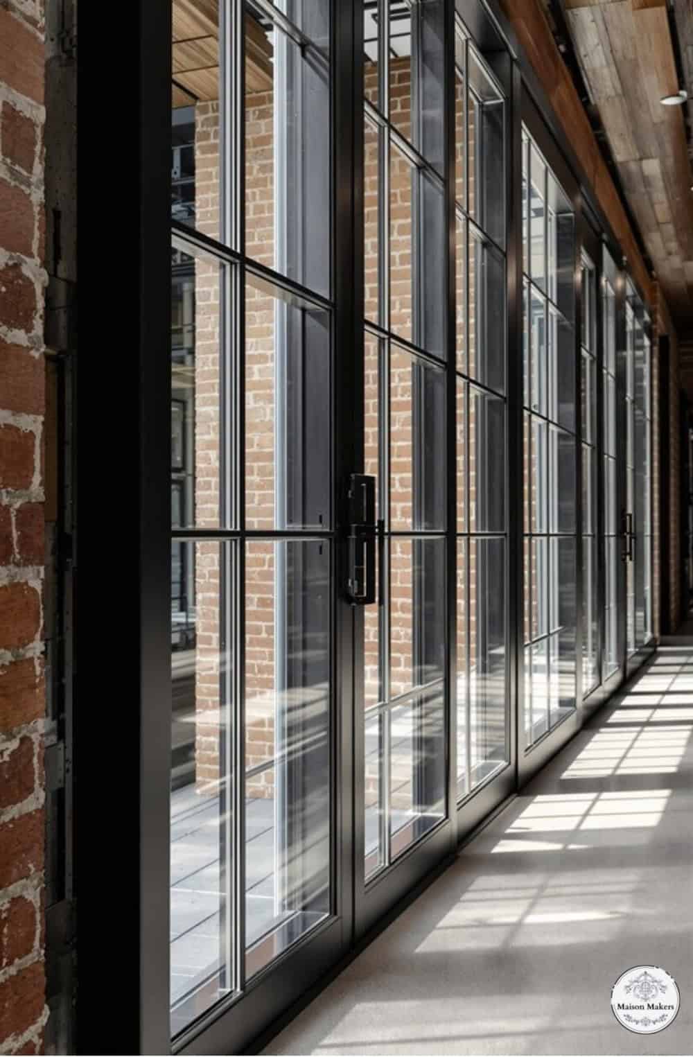a long hallway with a brick wall and windows