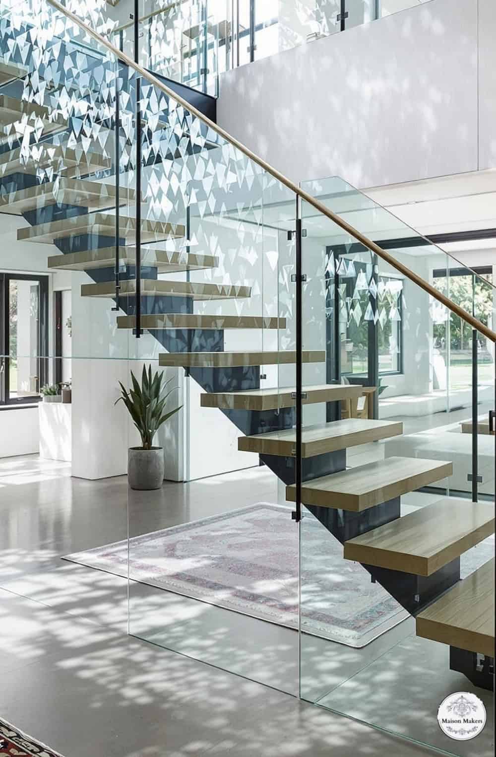 a stair case with glass railing and wooden steps