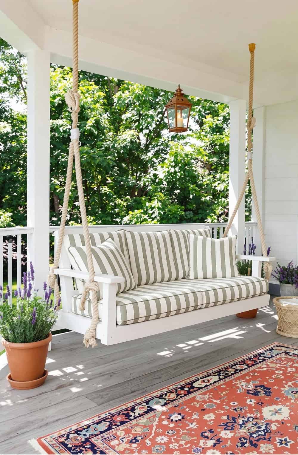 a porch swing with a rug and potted plants