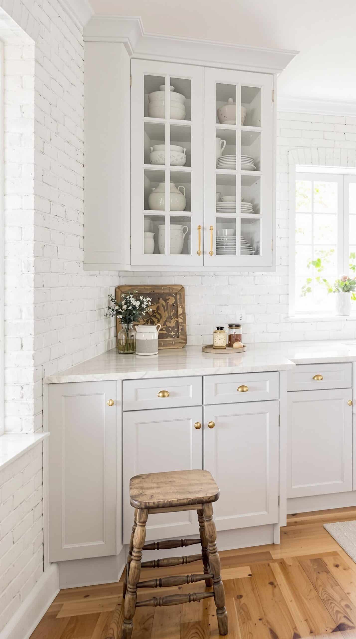a kitchen with white cabinets and a wooden stool