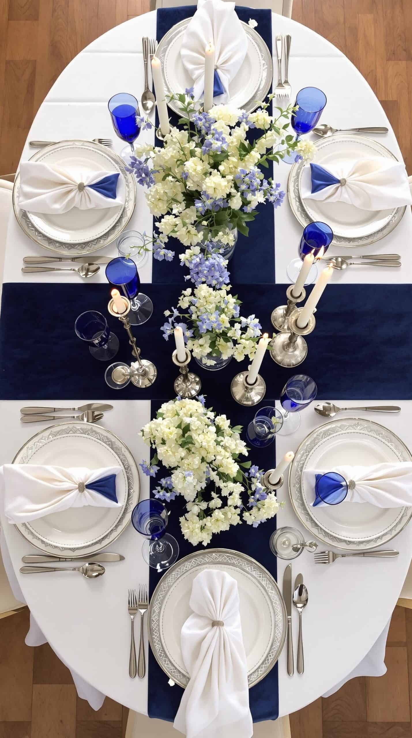 a blue and white table setting with flowers and silverware