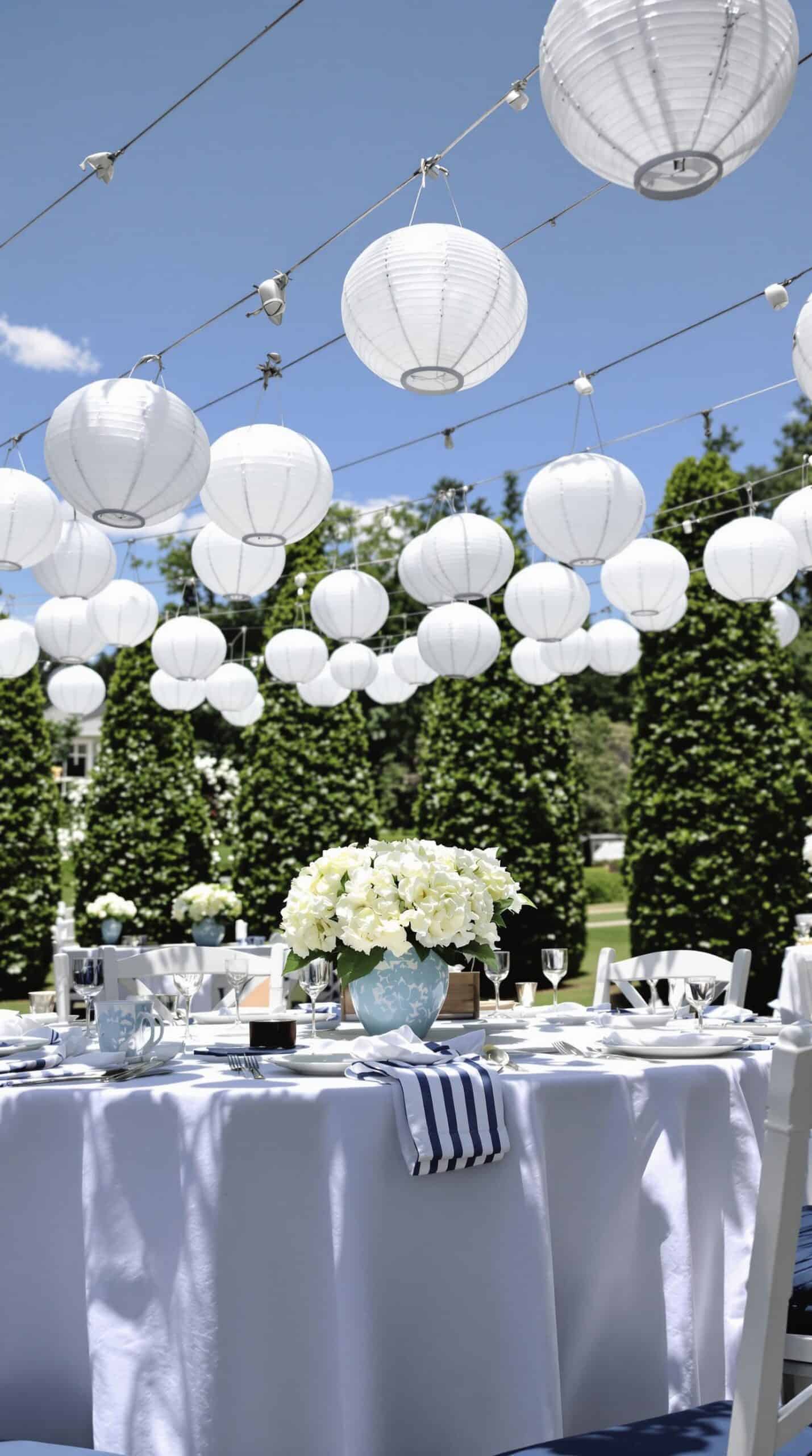 a table is set with white lanterns and flowers