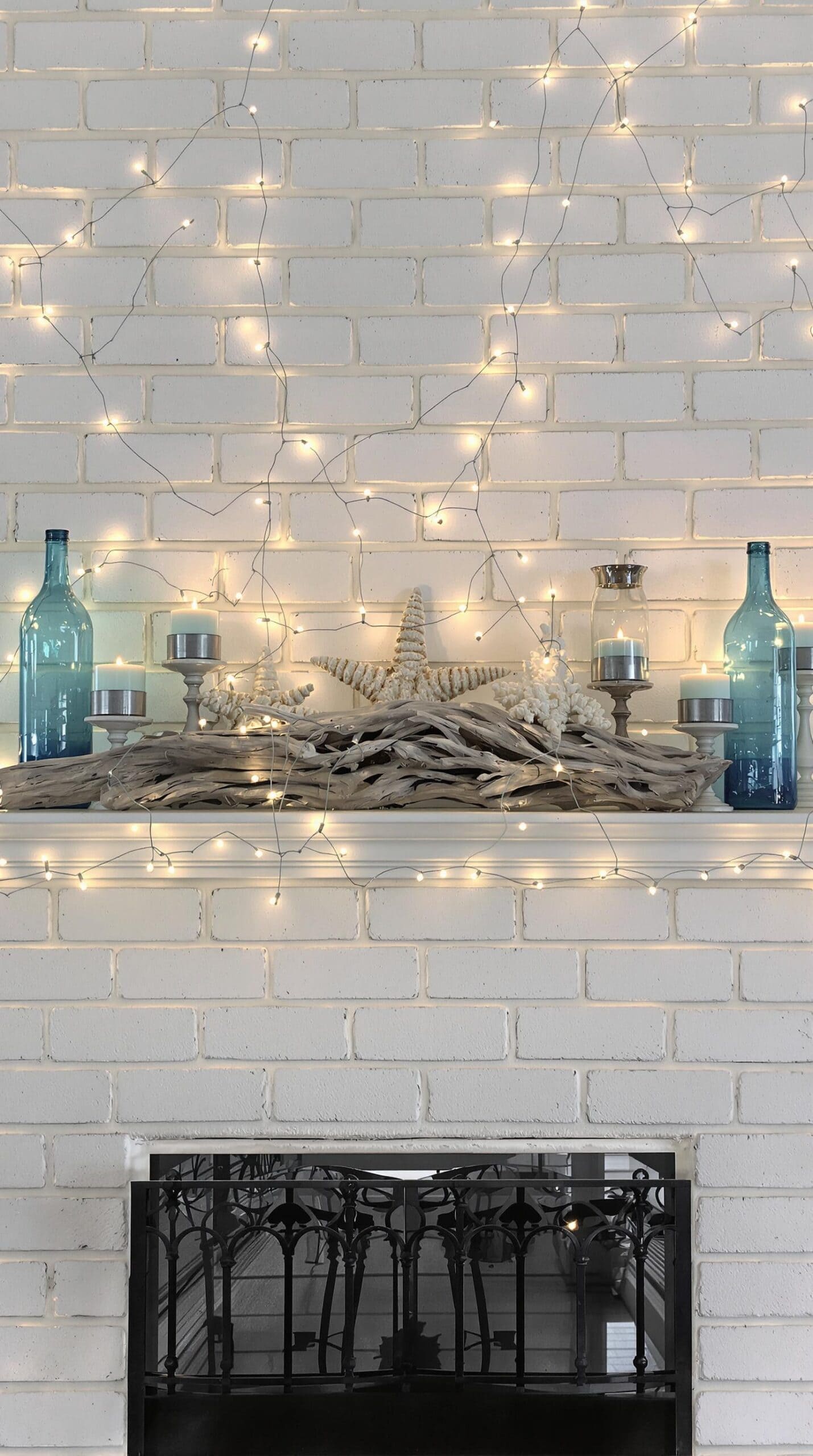 a white brick fireplace with a mantle decorated with lights