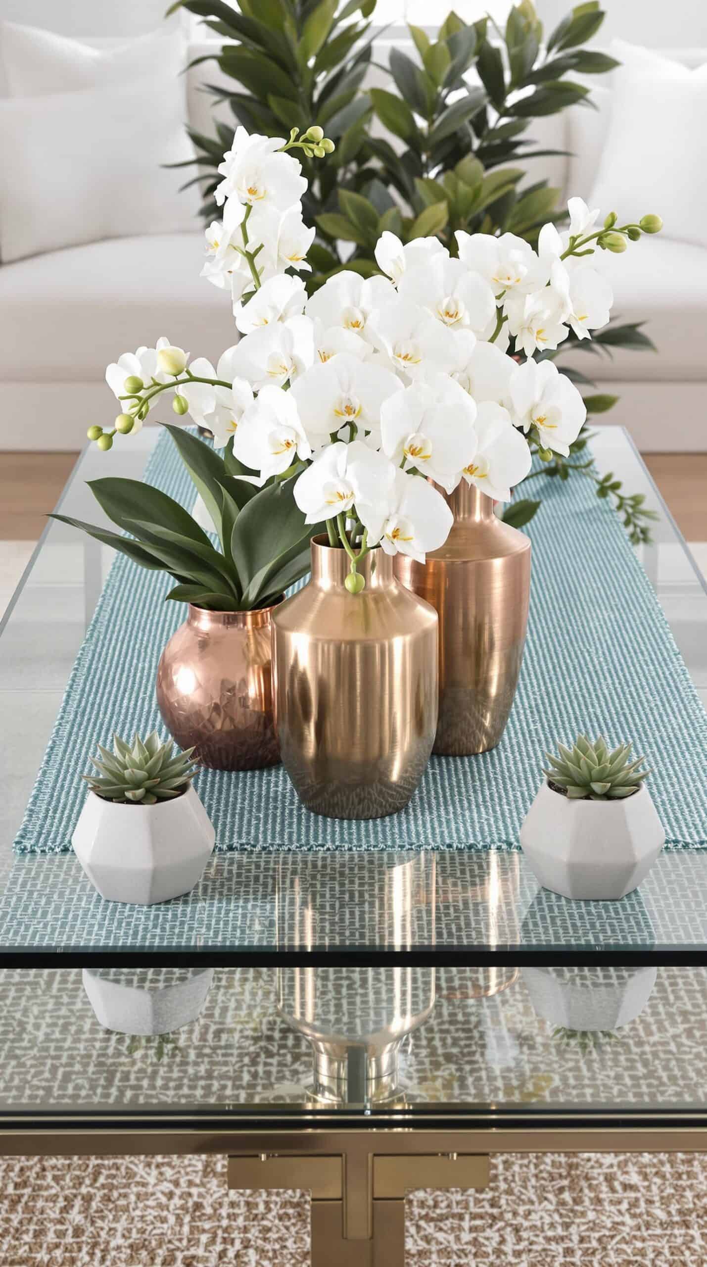 a glass table topped with three vases filled with flowers