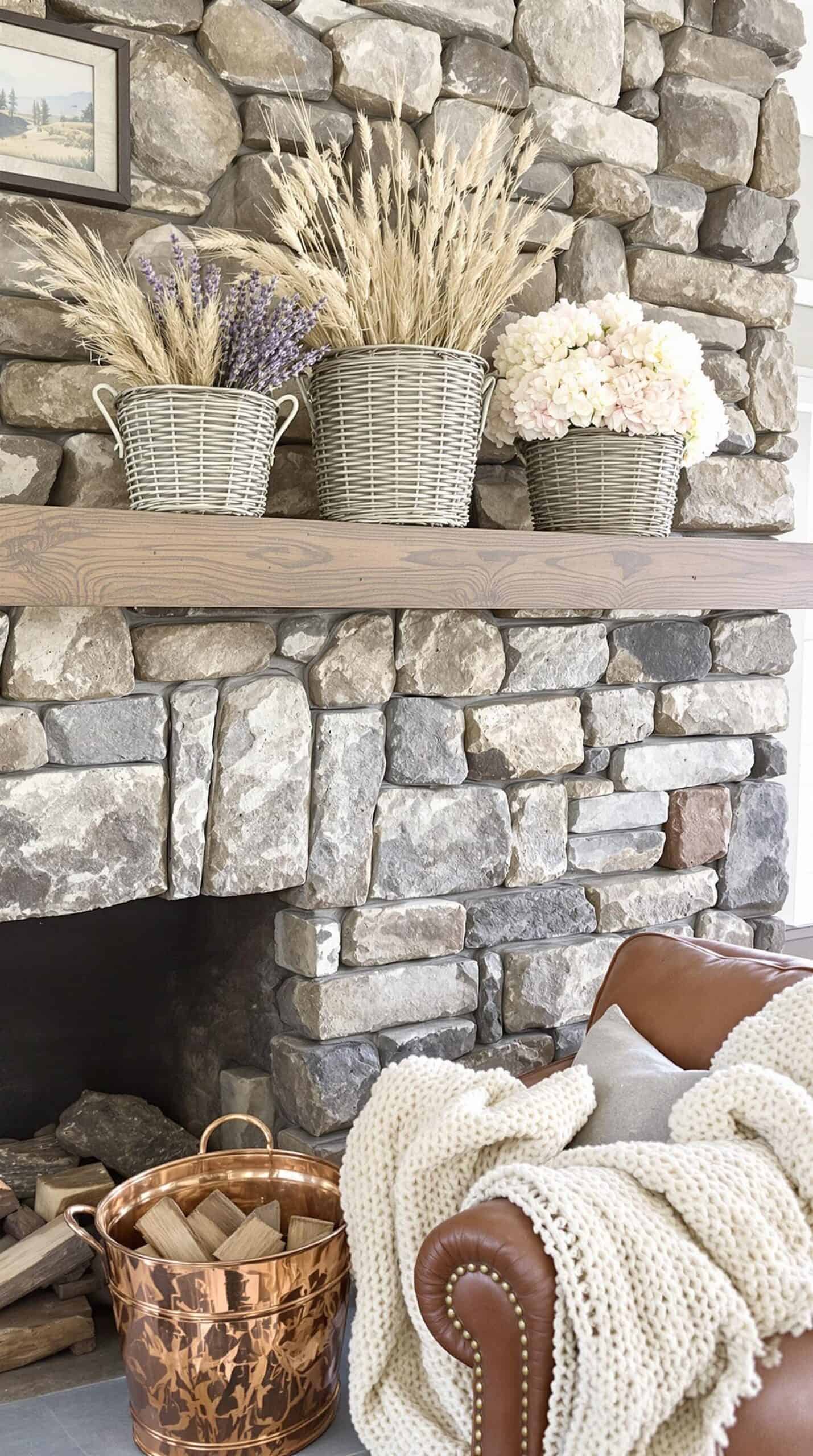 a living room with a stone fireplace and a basket of flowers